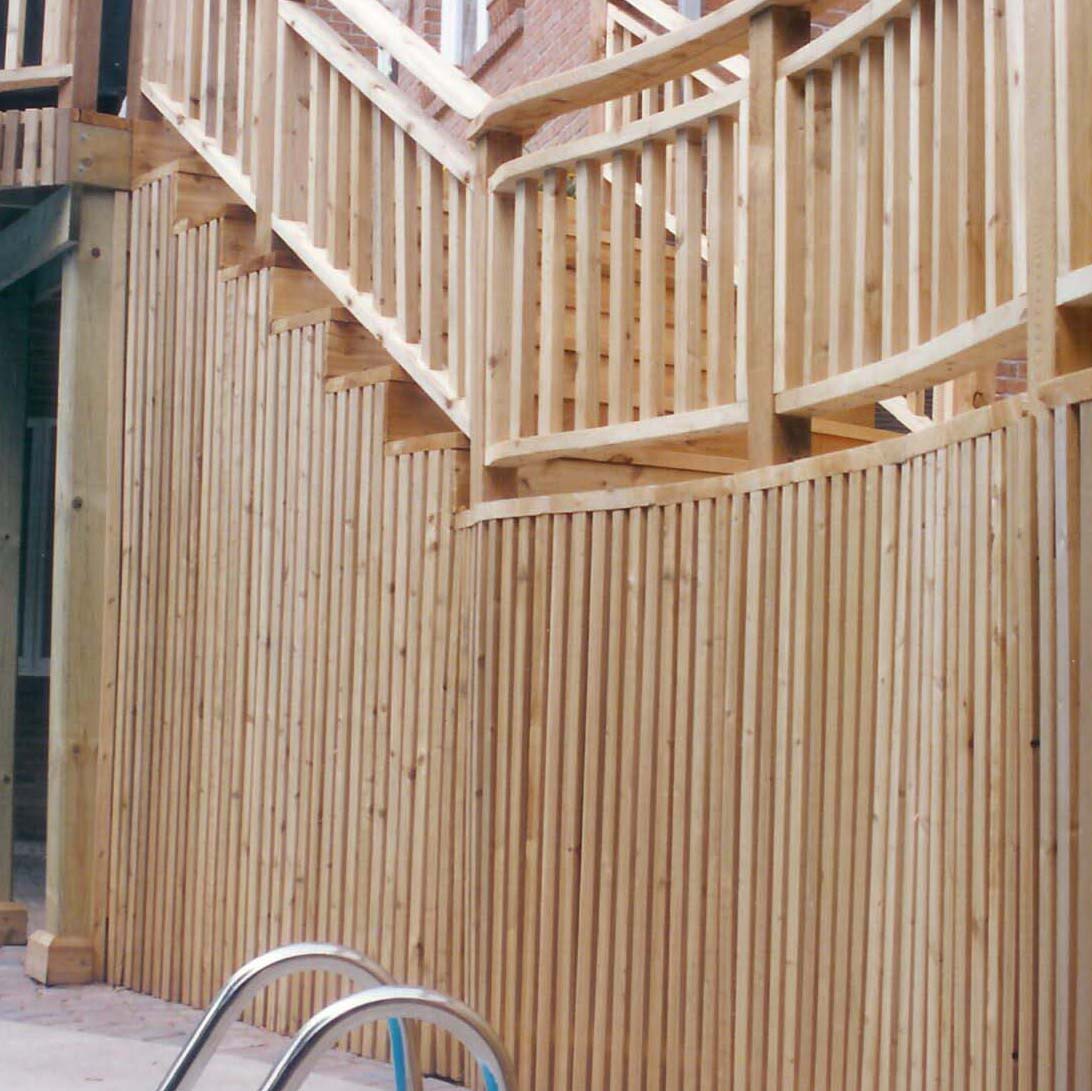 Wooden fence and staircase extend alongside a residential building. A pool ladder is visible in the foreground, suggesting a backyard setting.